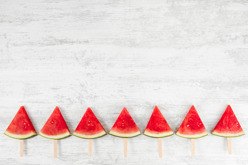 Watermelon slices on white wooden background with copy space