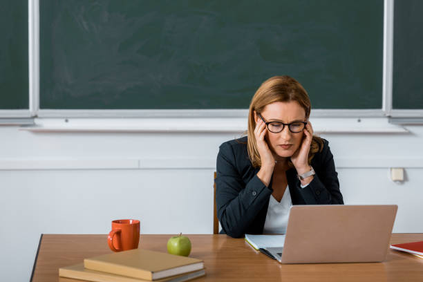 istock female teacher sitting at computer desk and having headache in class 1080232668