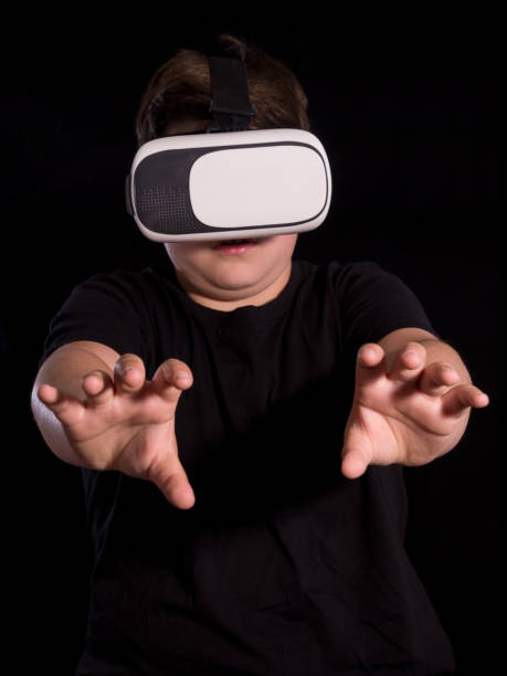 istock boy wearing a virtual reality glasses holding something with his hands, isolated on black background. 1080236180