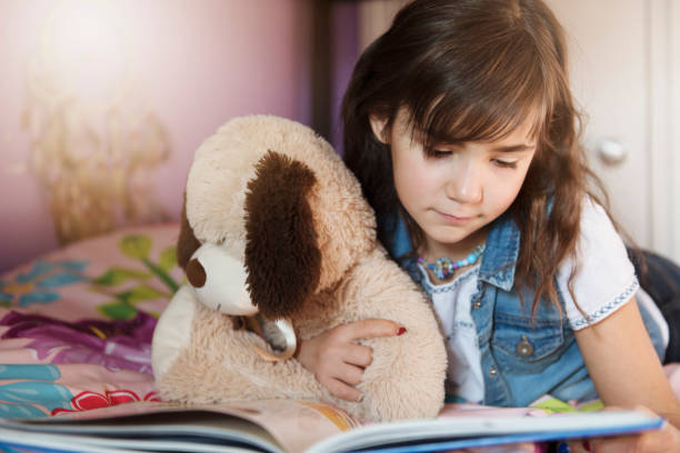 istock 7 years old girl reading a book on bed 1080240324