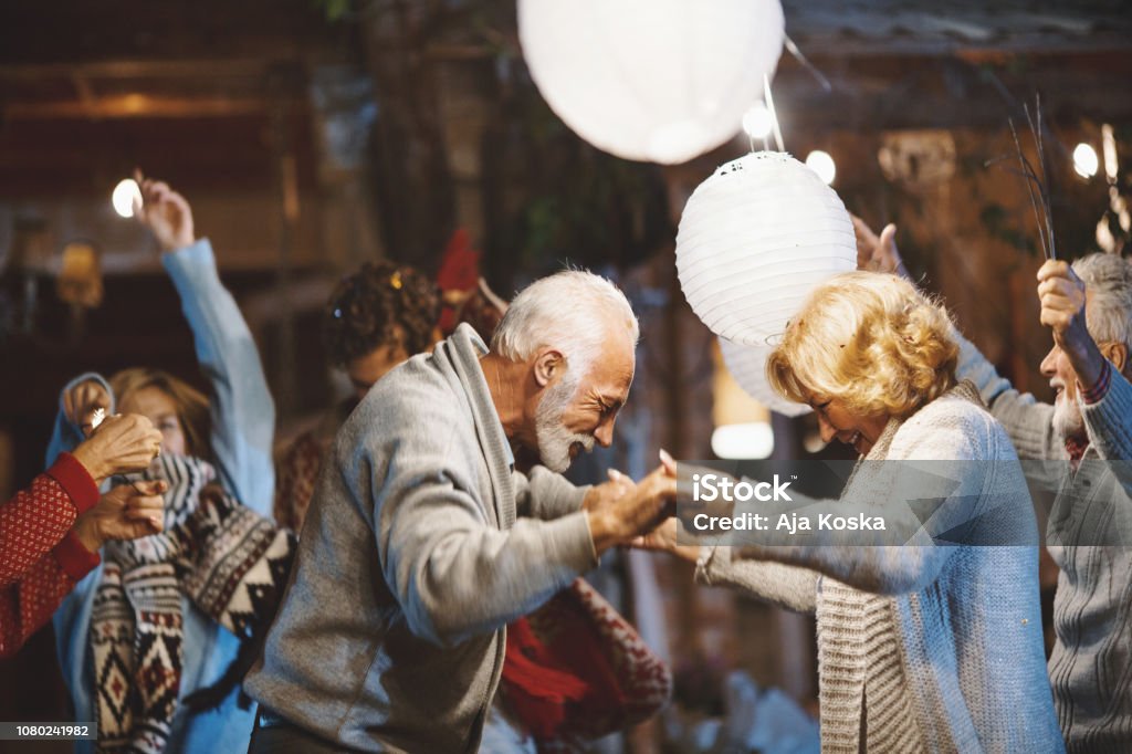 Family New Year's Eve Party. Senior couple dancing and celebrating New Year's Eve outdoors. Senior Adult Stock Photo