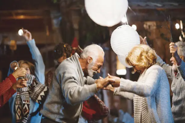 Senior couple dancing and celebrating New Year's Eve outdoors.