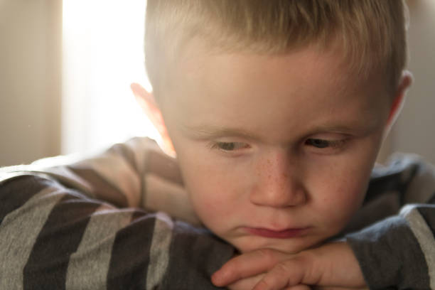 Little boy with his hands on his face not unimpressed with having his pictures taken.