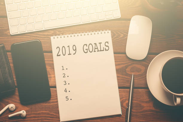 istock 2019 GOALS - text on notepad on wooden table, working place top view with coffee, smartphone, keyboard and business success checklist in sunlight 1080261578