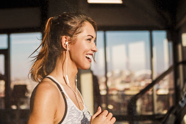 happy sweaty woman running on treadmill in a gym - healthy lifestyle dieting indoors lifestyles imagens e fotografias de stock