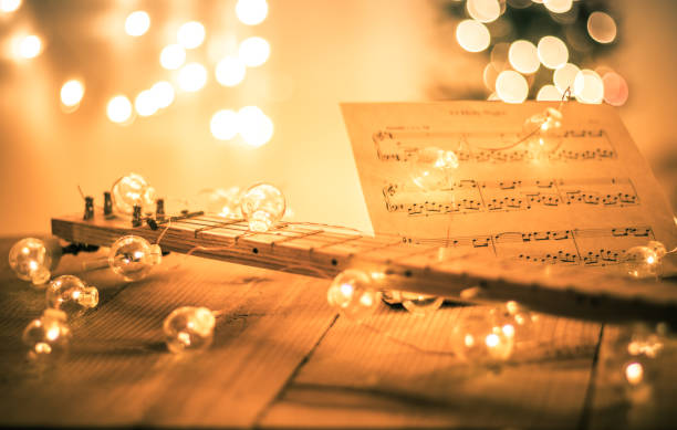 Cigar box guitar with instrumental sheet music and soft lights for Christmas holiday, split tone stock photo