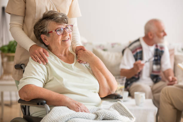 felice anziana seduta sulla sedia a rotelle in casa di cura per anziani - patient retirement senior adult hospital foto e immagini stock