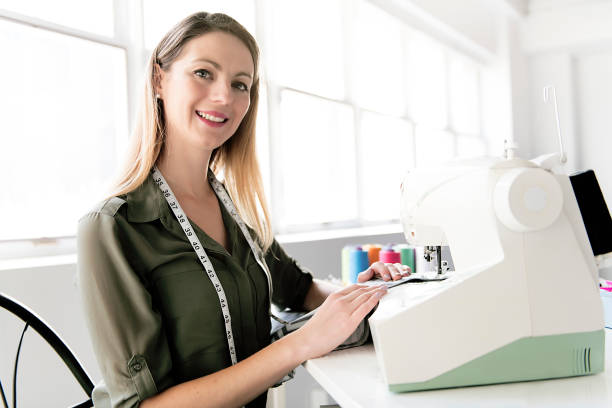istock Positive young woman sewing with professional machine at workshop 1080286710