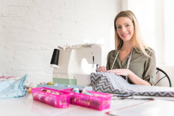 istock Positive young woman sewing with professional machine at workshop 1080286736