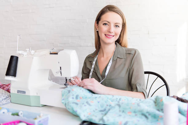 istock Positive young woman sewing with professional machine at workshop 1080286762