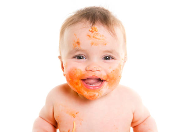 A Little baby eating her dinner and making a mess on his face