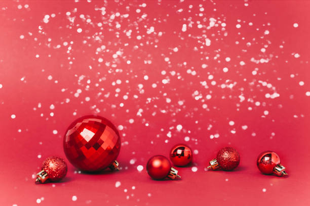 istock Christmas red background with christmas balls and snow falling on them. 1080301532
