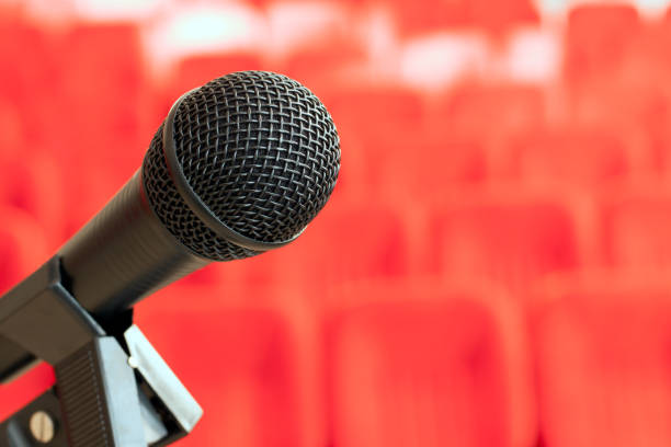 istock microphone on the stand in an empty assembly hall with red chairs. concept of trainings, business meetings and conferences. bright red background. 1080308700