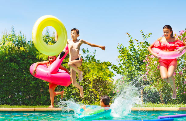 istock Joyful teens jumping into water with pool toys 1080308762