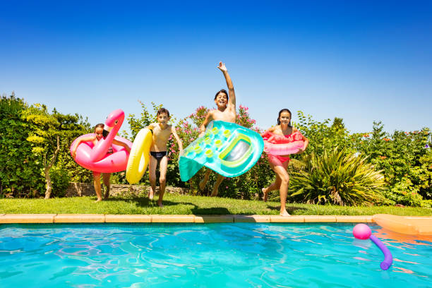 happy children running and jumping into the pool - inflatable child jumping leisure games imagens e fotografias de stock