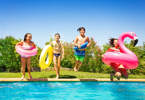 Happy teenage boys and girls with swimming tools, jumping into the water