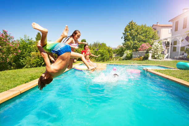 active teens spending summertime by the pool - inflatable child jumping leisure games imagens e fotografias de stock