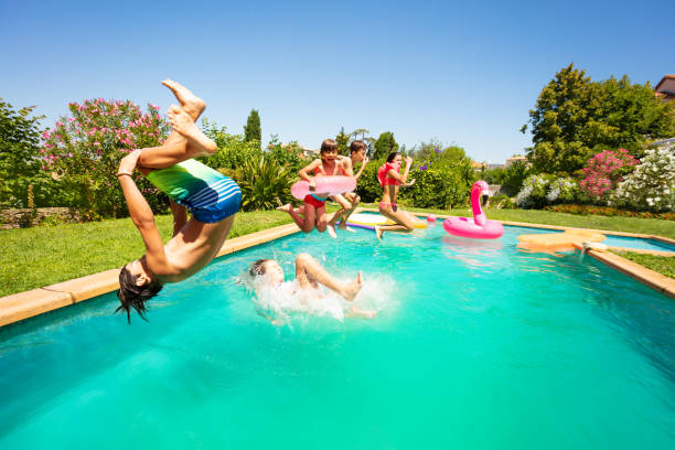 group of happy teens having fun in swimming pool - inflatable child jumping leisure games imagens e fotografias de stock