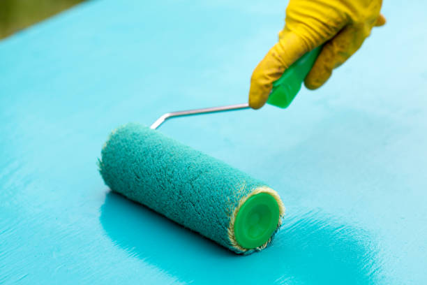 istock paint roller in hand and board with turquoise paint 1080312514
