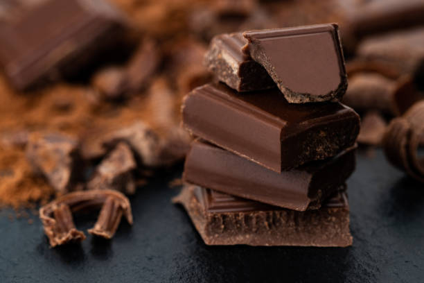 istock Broken chocolate pieces and cocoa powder on a dark background 1080315798