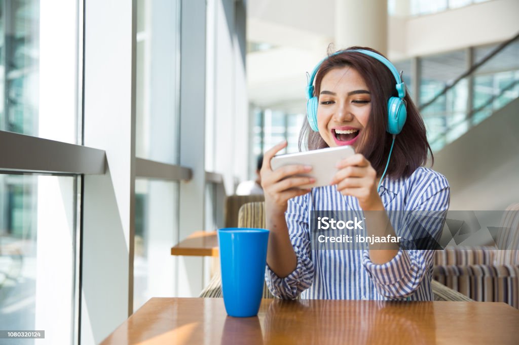 Girl playing mobile game at cafe Mobile Game Stock Photo