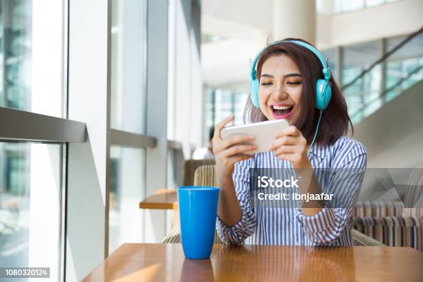 Girl Playing Mobile Game At Cafe Stock Photo - Download Image Now - Mobile Game, Asian and Indian Ethnicities, Mobile Phone