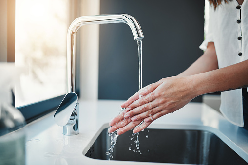 Cropped shot of an unrecognizable woman washing her hands in the kitchen sink