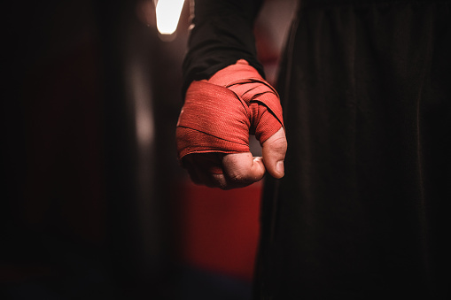 One man, kickboxer with wrapped boxing bandages on hand.