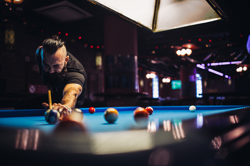 Bearded man playing snooker in a pub