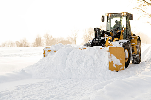 Un arado de nieve amarillo grande limpieza un camino photo