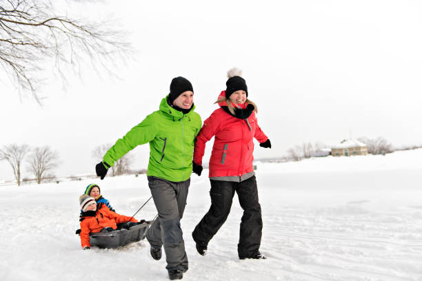 istock Cute Family Pulling Sledge Through Snowy Landscape 1080325386