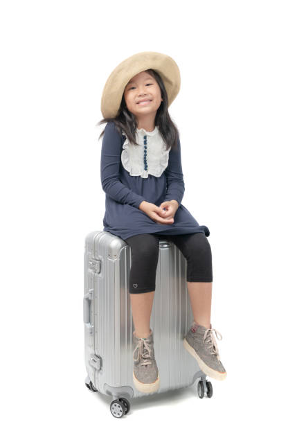 Happy traveler kid sit on baggage isolated on white background, travel concept