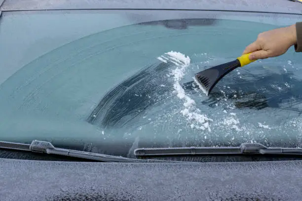 Photo of Hand scratching ice from car window