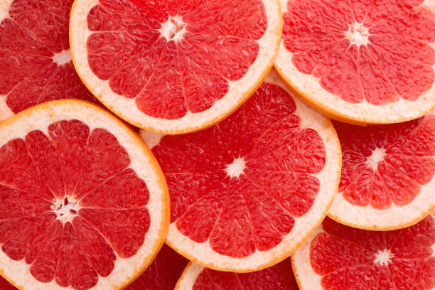 Close-up Grapefruit slices abstract background in Living Coral color. Close-up Grapefruit slices abstract background in Living Coral color of the Year 2019. Bright summer texture. grapefruit photos stock pictures, royalty-free photos & images