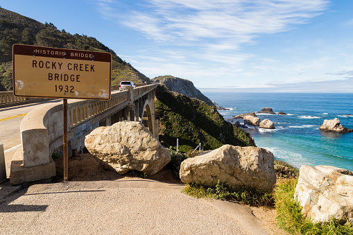 Historic Rocky Creek (Bixby Creek) bridge with sign and view of ocean from the Pacific Coast highway in California