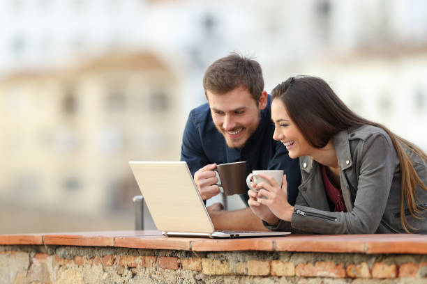 istock Happy couple using a laptop and drinking on vacation 1080329238