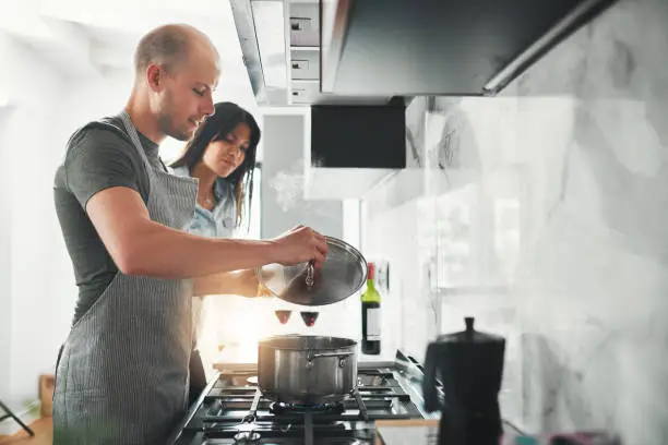 Shot of a young couple preparing a meal together in the kitchen at home