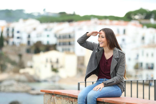 istock Happy woman scouting on a ledge on vacation 1080329418