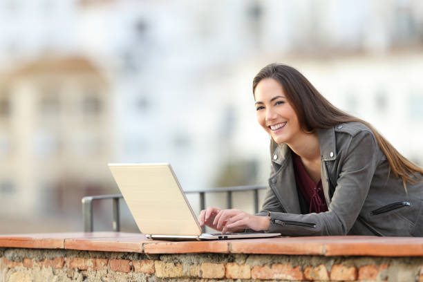 istock Happy woman using a laptop looks at camera on vacation 1080329474