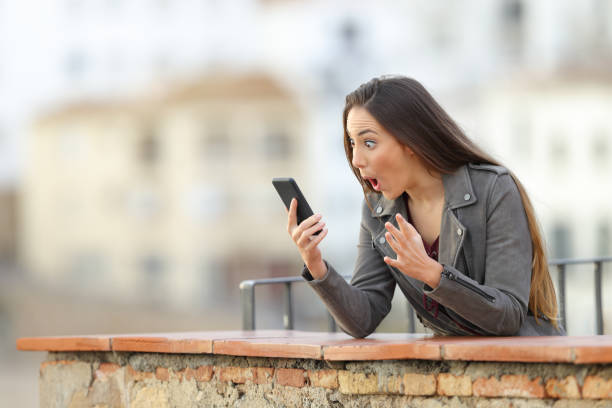 istock Surprised woman using a smart phone in a terrace 1080329550