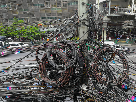 Bangkok, Thailand - November 29, 2018: Messy telephone line, fiber optic cable, TV cable which all are installed on the  electricity post in Bangkok, Thailand.