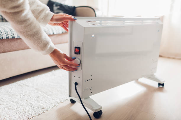 Using heater at home in winter. Woman regulating temperature on heater. Heating season. Using heater at home in winter. Woman regulating temperature on heater on wearing warm clothes. Heating season. heat home interior comfortable human foot stock pictures, royalty-free photos & images