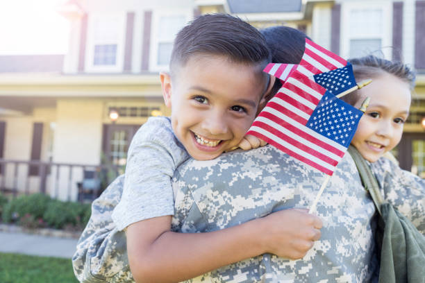 jeune garçon sourit car il détient des drapeaux et des caresses de sa mère en uniforme - usa child flag the americas photos et images de collection