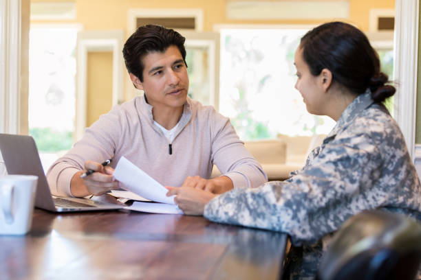 istock Woman in uniform sits at a table with a man as they look through papers 1080345402