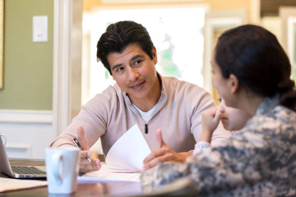 istock Man sits at a table with his wife in uniform as they discuss papers 1080345418