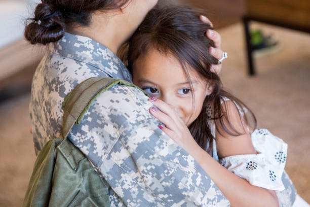 istock Little girl is pulled into a hug by her mother in uniform 1080345440