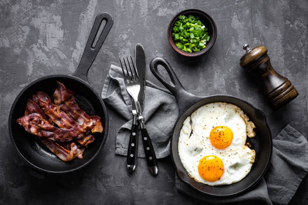 istock breakfast or brunch fried bacon and eggs in black skillets and top view 1080349588