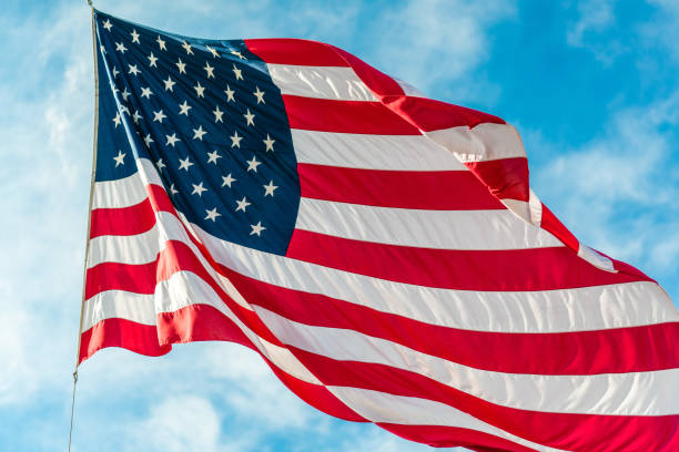 istock American flag waving in blue cloudy sky 1080350142