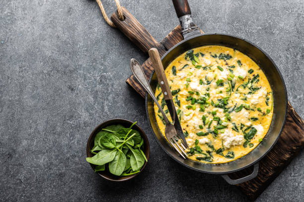 omelette aux épinards et fromage dans une casserole sur la vue de dessus de fond béton - poêle verte photos et images de collection