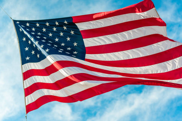 istock American flag waving in blue cloudy sky 1080351212
